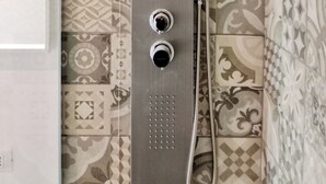 A shower with a handheld showerhead and a wall-mounted faucet, set against a patterned tile wall. - Cozy apartment in historic country residence, between Perugia and Assisi (Perugia)