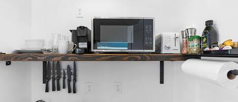 A compact kitchen with a microwave, coffee maker, and various kitchen utensils.
