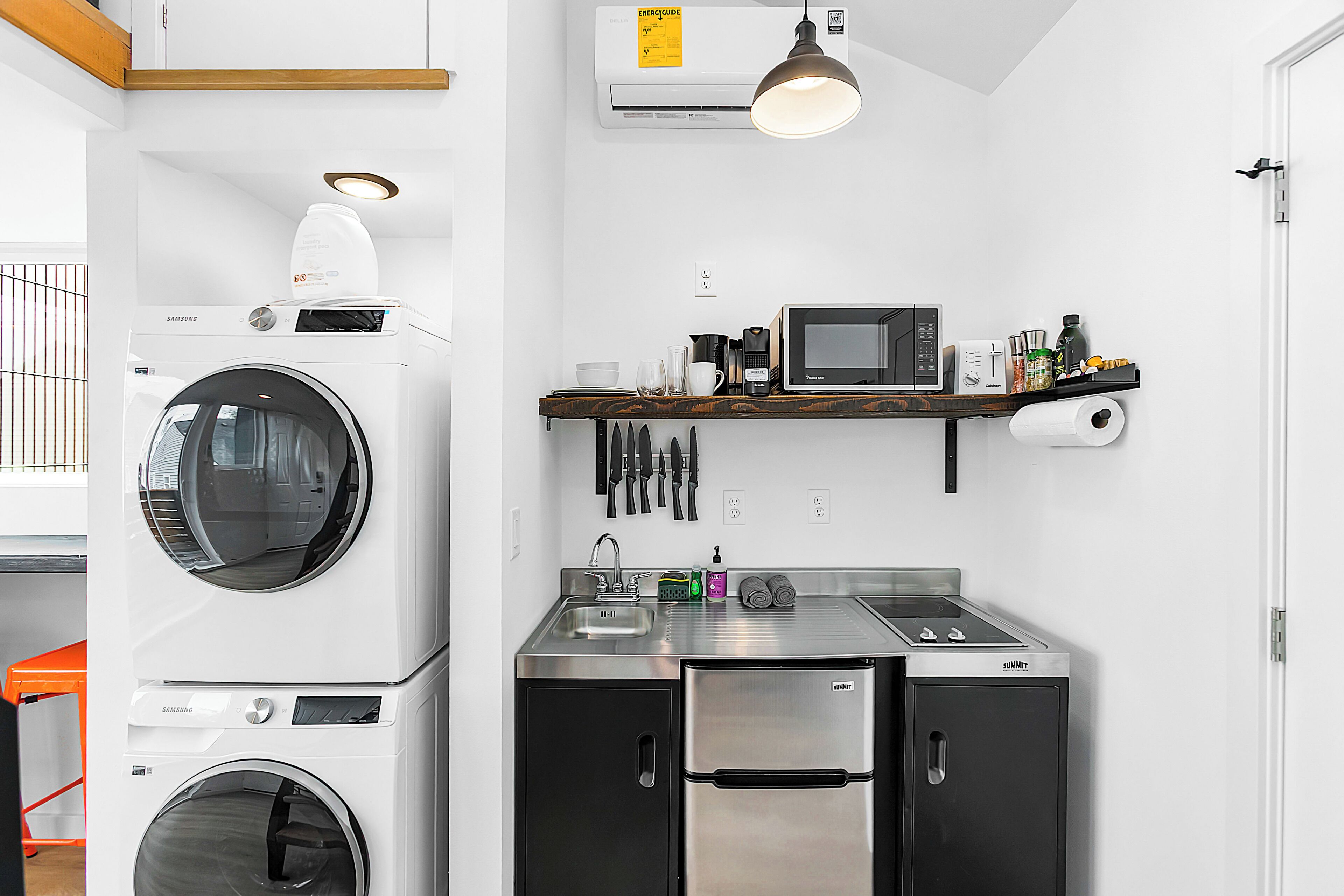 Une cuisine compacte équipée d’un lave-linge, d’un four à micro-ondes, d’un évier et d’une cuisinière.
