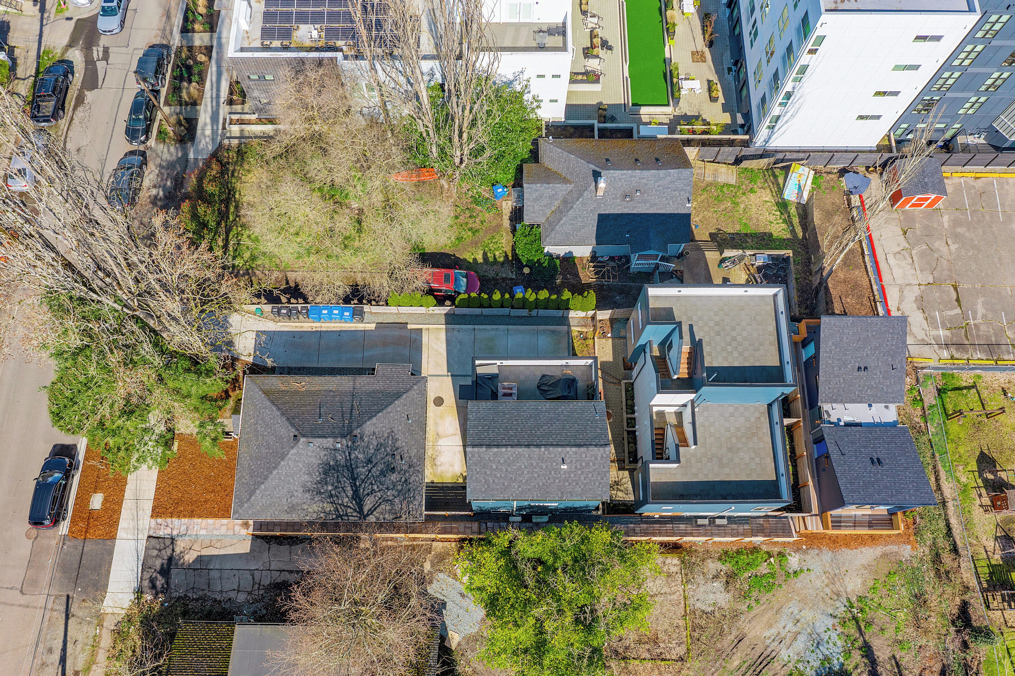 An aerial view of a residential area with multiple houses, a parking lot, and a small green space.