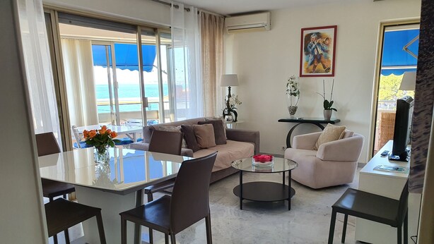 A modern living room with a glass dining table, two sofas, a coffee table, and a TV.