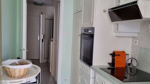 A kitchen with white cabinets, a black oven, and a coffee machine.