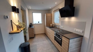 A modern kitchen with wooden cabinets, a black countertop, and a built-in oven.