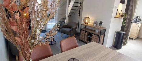 Et moderne spiseområde med et træbord, to sorte lysestager og en vase med tørrede planter.