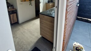 A modern kitchen with a wooden countertop, a coffee machine, and a hanging light fixture.