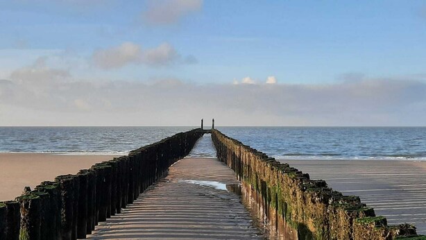 A pier extending into the sea with a clear sky above.