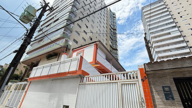 Een modern gebouw met een hekpoort, een betegelde gevel en meerdere balkons.