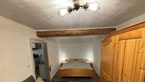 Un dormitorio con cama, armario y banca de madera, y una puerta que da a un baño.