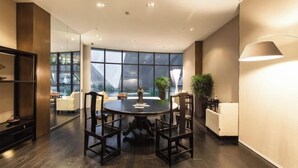 A modern conference room with a round table, dark wooden chairs, and a large window offering a view of the cityscape. - Hotel MoMc (Beijing)