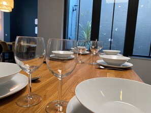 Une table à manger avec des assiettes, des bols et des verres à vin blancs, disposés pour un repas.