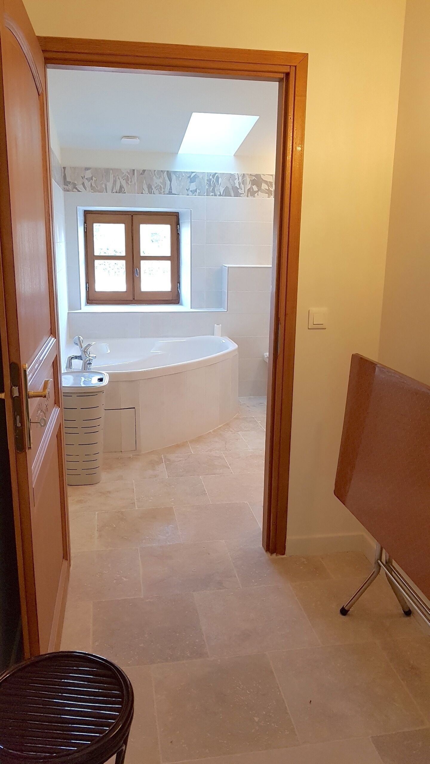 Een badkamer met een bad, een raam en een wastafel.