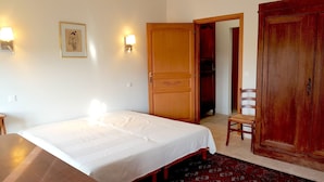 A bedroom with a bed, two wall-mounted lamps, a wooden door, and a chair. - Provence: Crossing city apartment, quiet, very bright, terrace. 2 stars. (VALREAS)