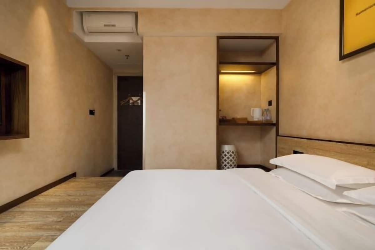Una habitación de hotel con una cama, un armario y un pequeño estante con artículos de aseo.