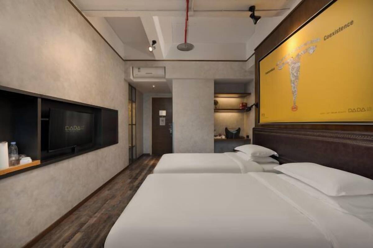 Habitación de hotel con cama, televisión montada en la pared y un cartel grande en la pared.