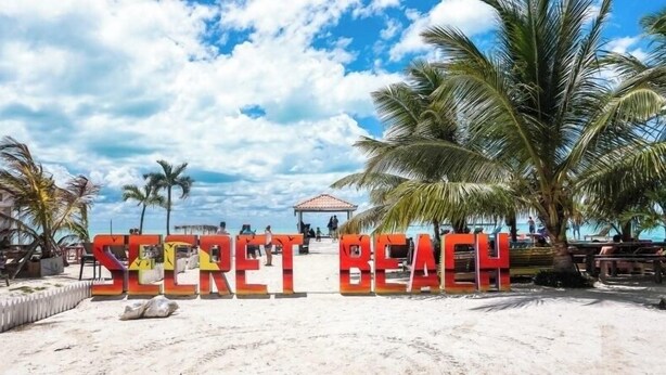 Une plage sur laquelle on peut lire, en grandes lettres, les mots « PLAGE SECRÈTE ».