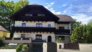 A two-story house with a dark roof, white walls, and a black front gate. - Vacation apartment Schlossblick (Salzburg)