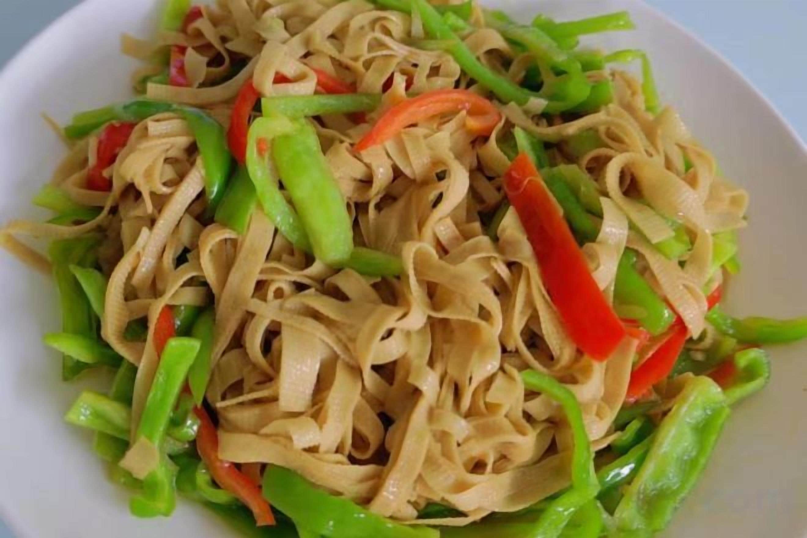 A plate of stir-fried noodles with vegetables.