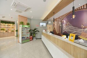 A reception area with a counter, a vending machine, and a wall-mounted TV. - Juban Hotel (Hefei Yaohai Wanda Station Tang Subway Station Store) (Hefei)