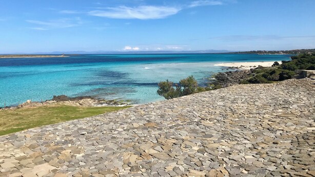 A coastal view with clear turquoise waters, a rocky foreground, and distant land. - Residence in Stintino 50 mt from the sea (Stintino)