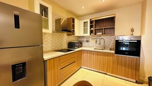 Eine moderne Küche mit einem Edelstahlkühlschrank, einem Backofen von Bosch, Holzschränken und einer gefliesten Spritzschutzwand.