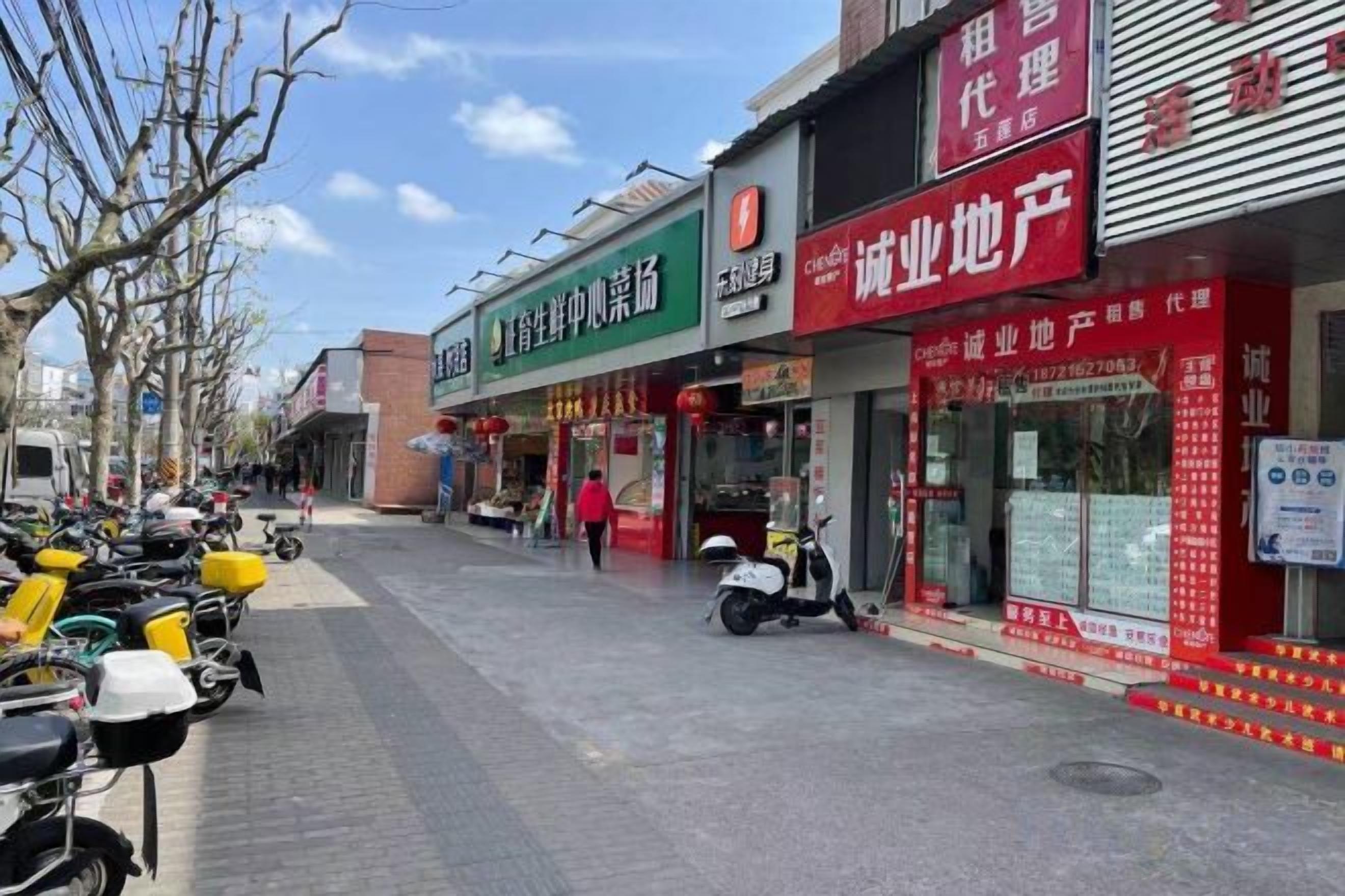 Una calle con tiendas y scooters estacionados.