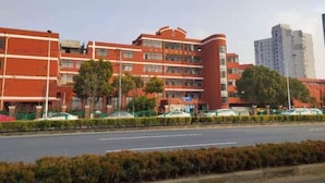 Un edificio de varios pisos con fachada roja, varias ventanas y una sección curva a la derecha.