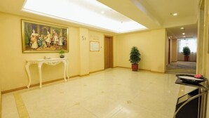 A hotel lobby with a tiled floor, a painting on the wall, a reception desk, and a potted plant. - Vienna 3 Best Hotel (Jingmen Wanda) (Jingmen)
