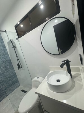 Ein modernes Badezimmer mit Toilette, Waschbecken und Spiegel.