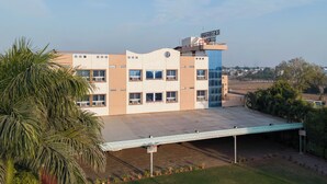 A multi-story building with a flat roof and a covered outdoor area. - Hotel Ruchi Shree Garden (Ujjain)