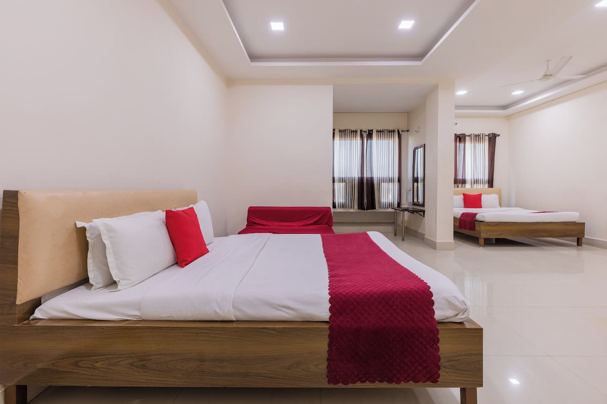 A modern hotel room with a large bed, a smaller bed, and a seating area.