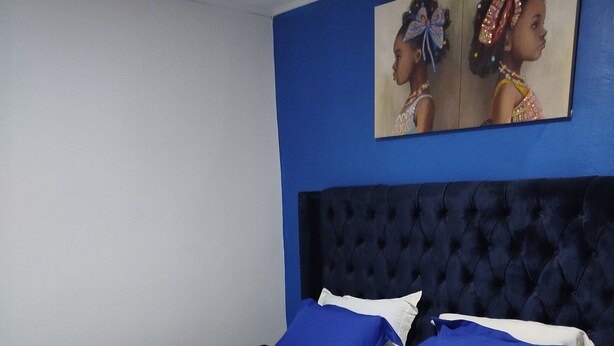 A bed with a blue headboard, white bedding, and blue and white pillows. - Hôtel Famigni (Douala)