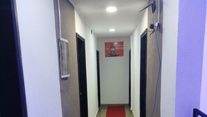 A hallway with a red carpet, white walls, and black doors. - Hôtel Famigni (Douala)