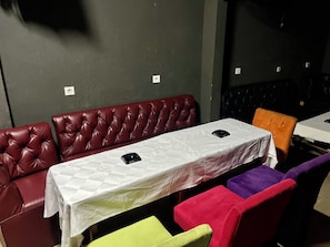 Uma área de refeições com uma mesa posta para dois, assentos acolchoados e um interruptor de luz fixado na parede.