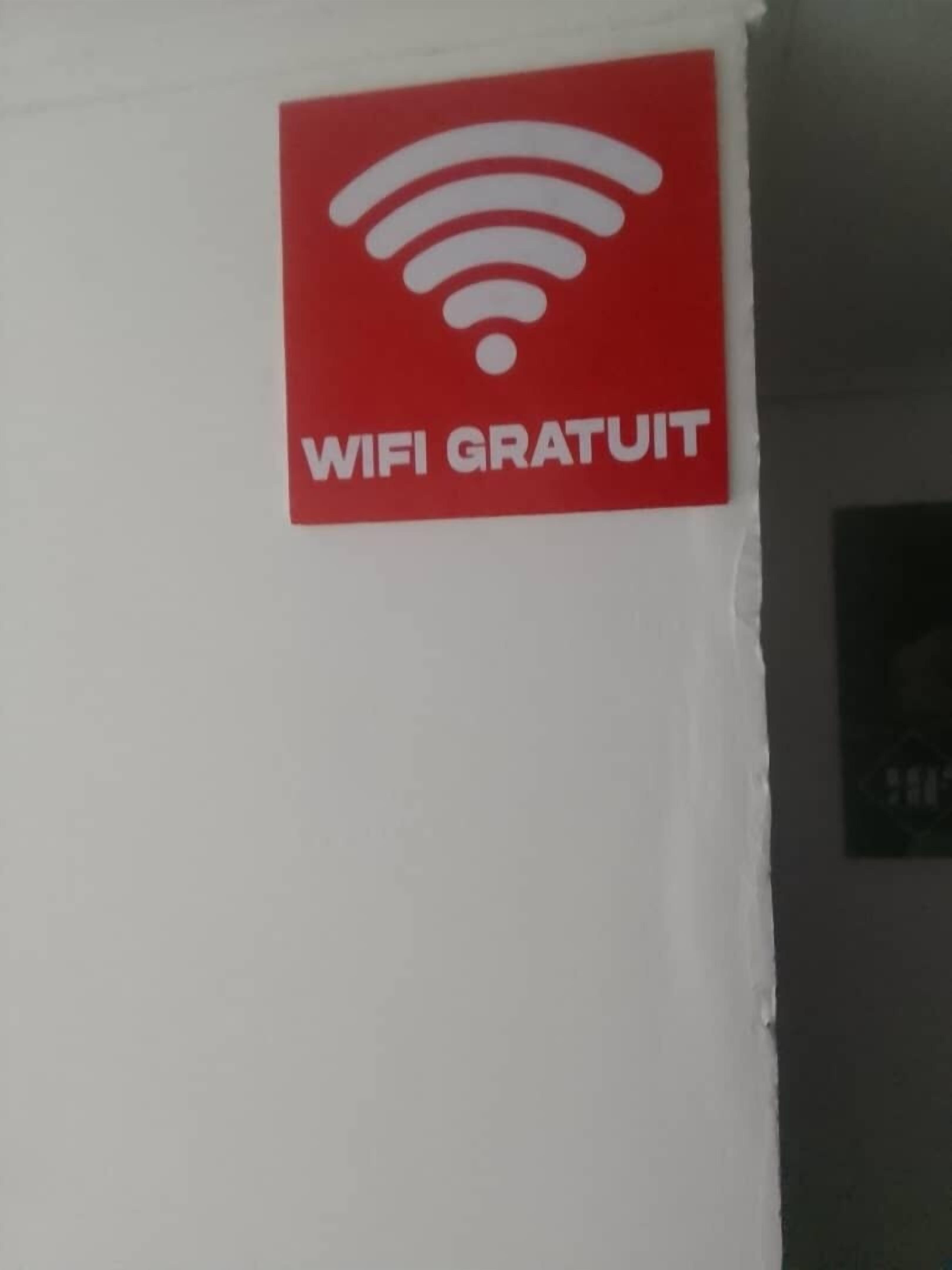 A red sign with a WiFi symbol and the text "WIFI GRATUIT" on a white wall.