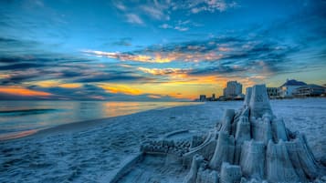 Una spiaggia con una grande struttura a forma di castello di sabbia in primo piano.