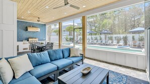 En moderne stue med en blå sofa, et spisebord og udsigt til en swimmingpool.