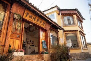 Un edificio tradicional de madera con un letrero, una entrada visible y una escalera que conduce a ella.