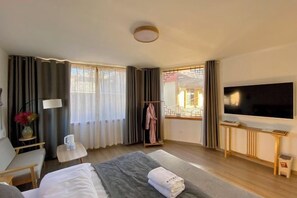 A hotel room with a bed, a TV, a desk, and a window with curtains. - Snowlake-Inn (Shangri-La)