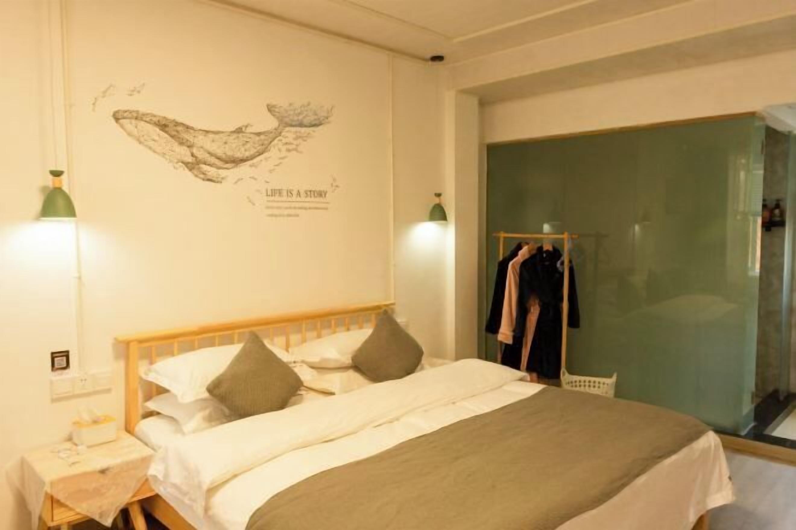 A bedroom with a bed, a wall with a whale illustration, and a closet with clothes.