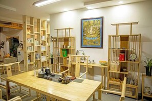 Een kamer met een houten tafel, stoelen, boekenkasten en een groot kunstwerk in een lijst aan de muur.