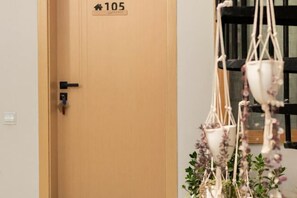 A door with a number sign, a hanging macrame plant, and a window with a black frame. - Snowlake-Inn (Shangri-La)
