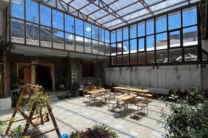 A greenhouse-style room with tables and chairs, large windows, and plants. - Snowlake-Inn (Shangri-La)