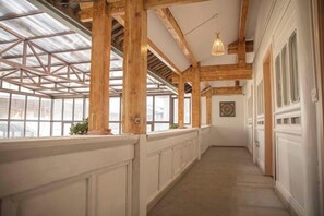 A corridor with wooden beams, large windows, and a hanging light fixture. - Snowlake-Inn (Shangri-La)