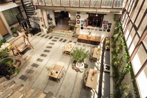 A spacious indoor area with multiple seating arrangements, a staircase, and a variety of plants. - Snowlake-Inn (Shangri-La)