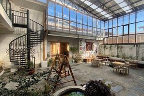 Un'ampia area interna con una scala a chiocciola, zone salotto e diverse piante.