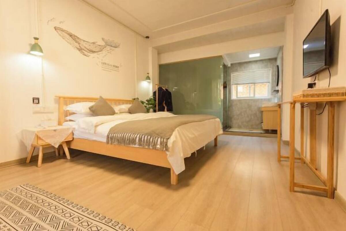 A bedroom with a bed, bedside table, lamp, and a television.