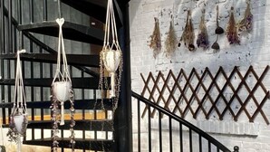 Una escalera adornada con decoraciones de macramé y flores secas en la pared.