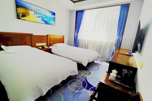 Una habitación de hotel con dos camas, un escritorio con cafetera, un televisor y un cuadro en la pared.
