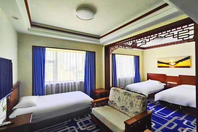 A hotel room with two beds, a sofa, a desk, and a TV.