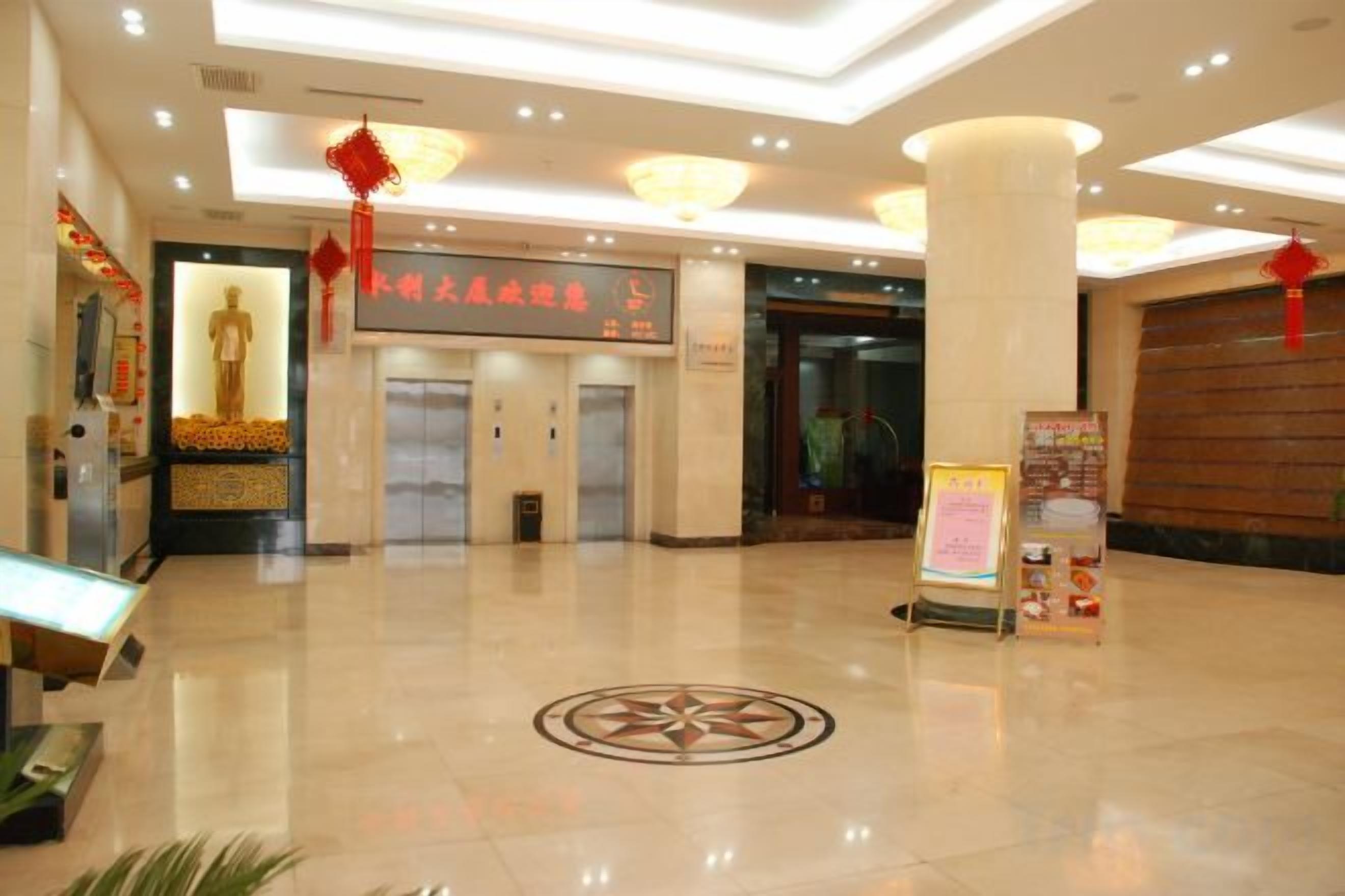 Vestíbulo de hotel con mostrador de recepción, ascensores y un diseño decorativo en el suelo.